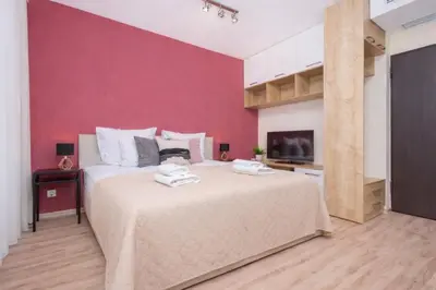 a bedroom with a large bed with a pink wall at InPoint Central Apartments in Kraków