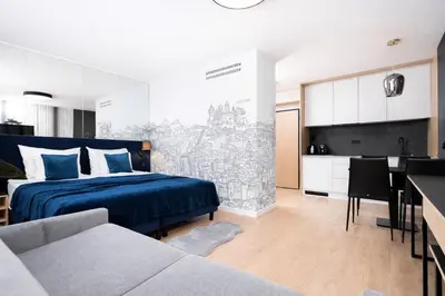 a bedroom with a blue bed and a kitchen at InPoint Central Apartments in Kraków