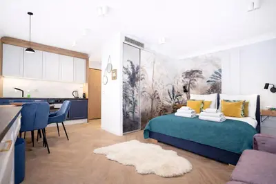 a bedroom with a green bed and a kitchen at InPoint Central Apartments in Kraków
