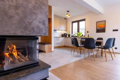 a living room with a fireplace and a table and chairs at Domki Gasiówka in Jaworzna