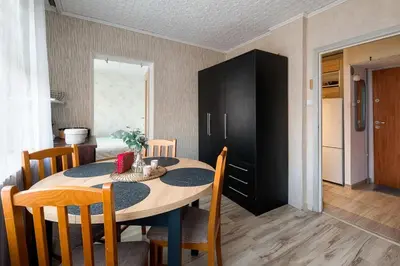 a dining room table with chairs and a black cabinet at Like home in Kraków