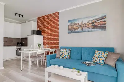 a living room with a blue couch and a kitchen at Cozy Apartment with Parking and Terrace in Kraków by Noclegi Renters in Kraków