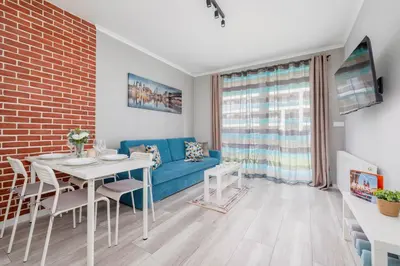 a living room with a blue couch and a table at Cozy Apartment with Parking and Terrace in Kraków by Noclegi Renters in Kraków