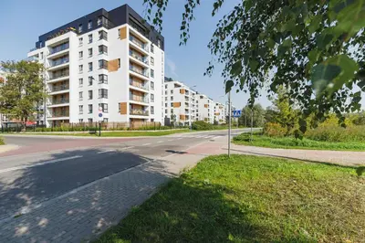 an empty street with a tall white apartment building at Cozy Apartment with Parking and Terrace in Kraków by Noclegi Renters in Kraków