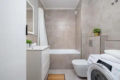 a bathroom with a toilet and a washing machine in it at Cozy Apartment with Parking and Terrace in Kraków by Noclegi Renters in Kraków