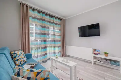 a living room with a blue couch and a tv at Cozy Apartment with Parking and Terrace in Kraków by Noclegi Renters in Kraków