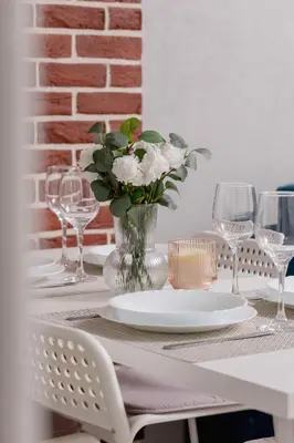 a table with glasses and a vase with white flowers at Cozy Apartment with Parking and Terrace in Kraków by Noclegi Renters in Kraków