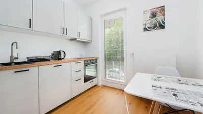 a kitchen with white cabinets and a table at Rakowicka Steam Park, Sun & Snow in Kraków