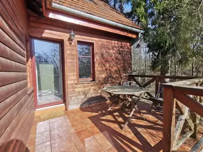 a wooden cabin with a picnic table on a patio at Domek Samotnia w ogrodzie in Kraków