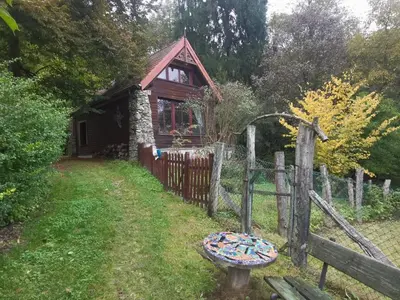 a log cabin with a fence and a table in the yard at Domek Samotnia w ogrodzie in Kraków