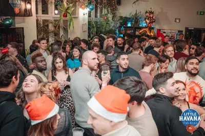 a group of people standing in a crowd at a christmas party at The Little Havana Party Hostel in Kraków
