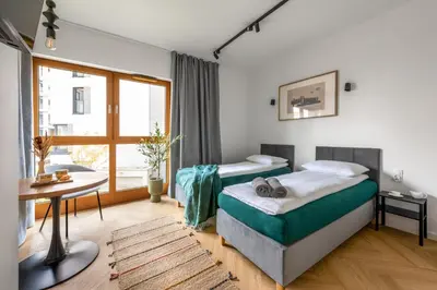 a bedroom with two beds and a table and a window at WLB Apartments in Kraków