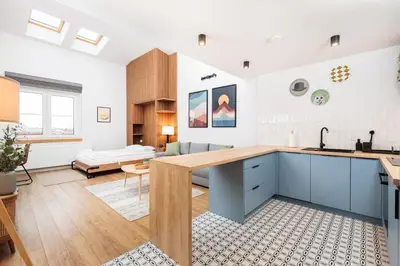 a kitchen with blue cabinets and a living room at Stylowe Studio - Nowy Kleparz - Kraków - by Upstairs in Kraków
