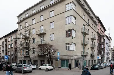 a large building on a city street with parked cars at Stylowe Studio - Nowy Kleparz - Kraków - by Upstairs in Kraków