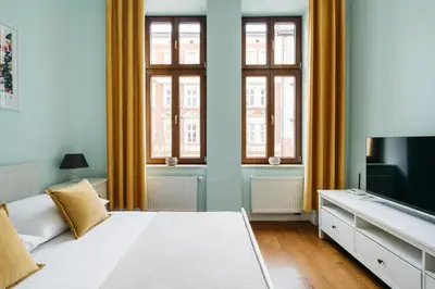 a bedroom with a white bed and two windows at Native Apartments Brzozowa 15 in Kraków