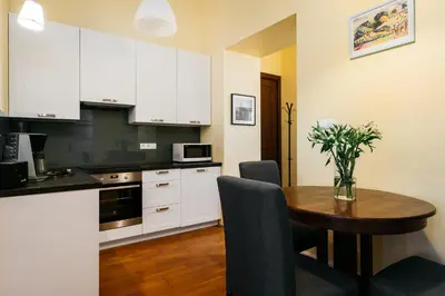 a kitchen with a wooden table and white cabinets at Native Apartments Brzozowa 15 in Kraków