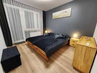 a bedroom with a bed and a table with two lamps at Grey Apartment Kraków in Kraków