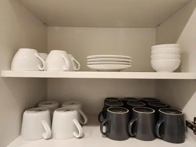 a shelf with dishes and cups and plates on it at Grey Apartment Kraków in Kraków