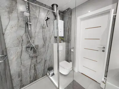 a bathroom with a shower with a toilet and a glass door at Grey Apartment Kraków in Kraków