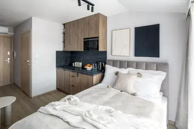 a bedroom with a white bed and a kitchen at Iron Street by A11 Sauna in Kraków