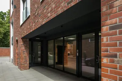 an entrance to a brick building with glass doors at Iron Street by A11 Sauna in Kraków