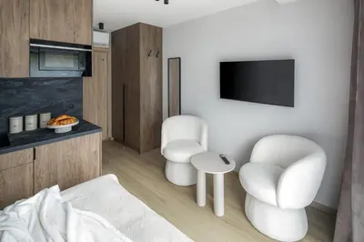 a living room with two white chairs and a tv at Iron Street by A11 Sauna in Kraków