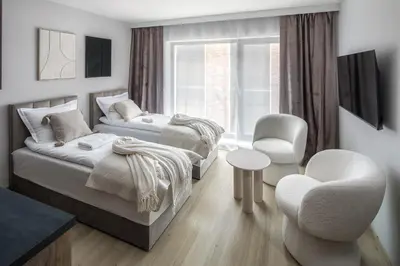 a bedroom with two beds and a chair at Iron Street by A11 Sauna in Kraków