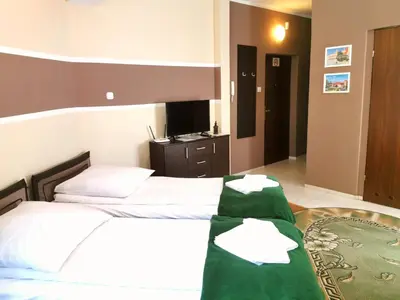 a bedroom with two beds and a table with towels at Apartamenty Dolna Kraków in Kraków