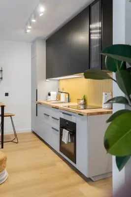 a kitchen with black and white cabinets and a table at Bright and cosy flat near the river in Kraków