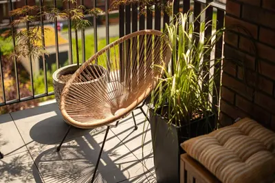 a chair sitting on a porch next to a plant at Bright and cosy flat near the river in Kraków
