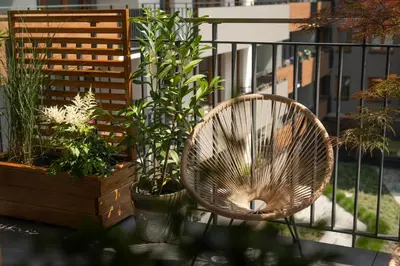 a rattan chair sitting on a balcony with plants at Bright and cosy flat near the river in Kraków