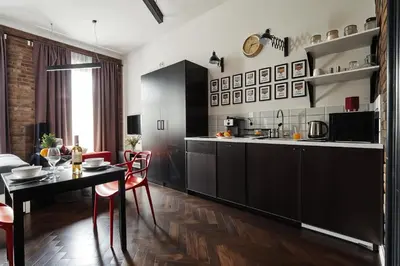 a kitchen with black cabinets and a table with red chairs at Cracow Fancy Brick #1 - Old Town in Kraków