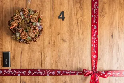 a christmas wreath on a wooden door with a red bow at Apartamenty Baj na Polnej - bezpłatny parking, widok na góry i zewnętrzna balia! in PyzÃ³wka