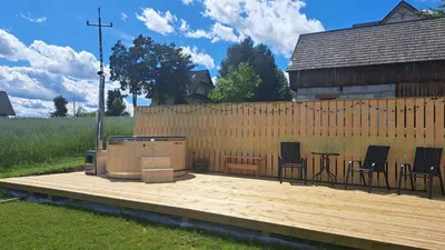 a deck with chairs and a table and a fence at Apartamenty Baj na Polnej - bezpłatny parking, widok na góry i zewnętrzna balia! in PyzÃ³wka