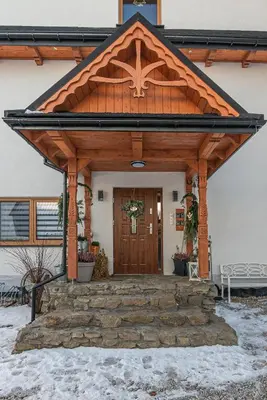 a front entrance to a house with a wooden door at Apartamenty Baj na Polnej - bezpłatny parking, widok na góry i zewnętrzna balia! in PyzÃ³wka