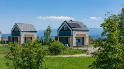 two houses in a field with trees at Domki z Widokiem Klikuszowa jacuzzi in Klikuszowa