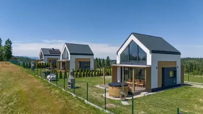 a row of houses in a field at Domki z Widokiem Klikuszowa jacuzzi in Klikuszowa