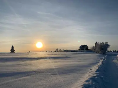 a snow covered field with the sun in the sky at Domki z Widokiem Klikuszowa jacuzzi in Klikuszowa