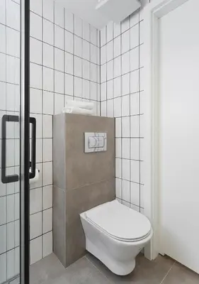 a bathroom with a toilet and a tiled wall at Golden Honey Apartments in Kraków