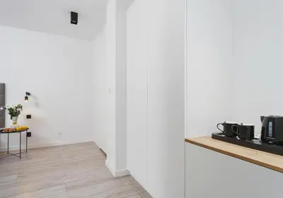 a living room with white walls and a wooden floor at Golden Honey Apartments in Kraków