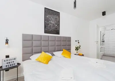 a bedroom with a large white bed with yellow pillows at Golden Honey Apartments in Kraków