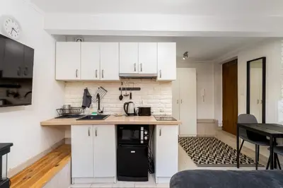 a kitchen with white cabinets and a black appliance at Park Kleparski Comfort Studio by BookingHost in Kraków