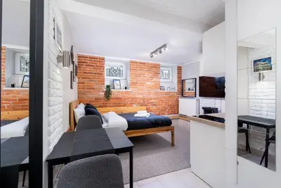 a living room and kitchen with a brick wall at Park Kleparski Comfort Studio by BookingHost in Kraków