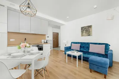 a living room with a blue couch and a table at Elegancki Apartament z Balkonem dla 4 osób by Noclegi Renters in Kraków