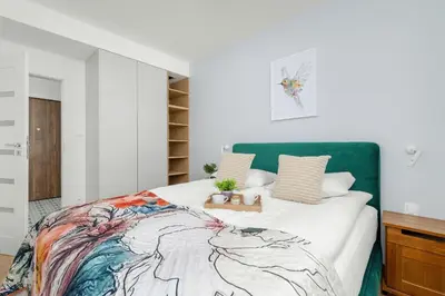 a bedroom with a large bed with a green headboard at Elegancki Apartament z Balkonem dla 4 osób by Noclegi Renters in Kraków