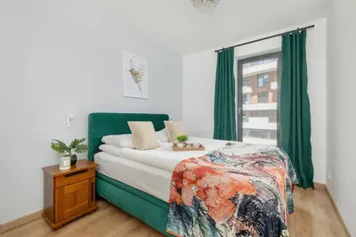 a bedroom with a bed with green curtains and a window at Elegancki Apartament z Balkonem dla 4 osób by Noclegi Renters in Kraków