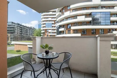 a table and chairs on a balcony with a building at Elegancki Apartament z Balkonem dla 4 osób by Noclegi Renters in Kraków