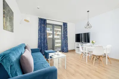 a living room with a blue couch and a table at Elegancki Apartament z Balkonem dla 4 osób by Noclegi Renters in Kraków
