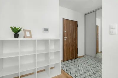 a hallway with white walls and a wooden door at Elegancki Apartament z Balkonem dla 4 osób by Noclegi Renters in Kraków