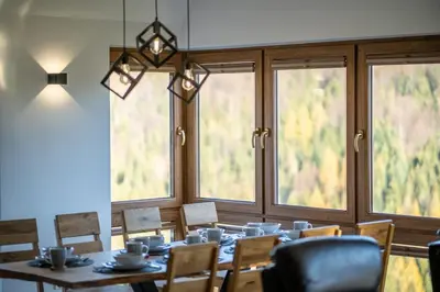 a dining room with a table and chairs and windows at Górski Dom dla 30 osób z sauna oraz salą do integracji in Kocierz Rychwałdzki